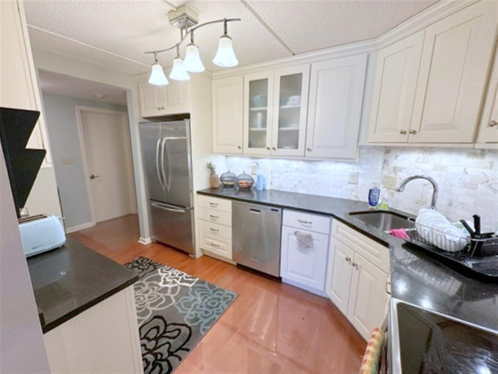 a kitchen with stainless steel appliances granite countertop a sink stove refrigerator and cabinets