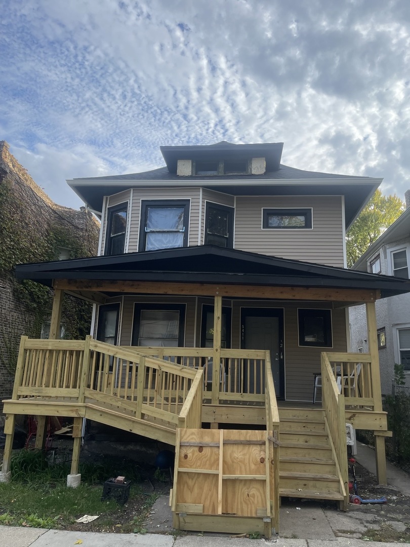 a view of house with a deck and a yard