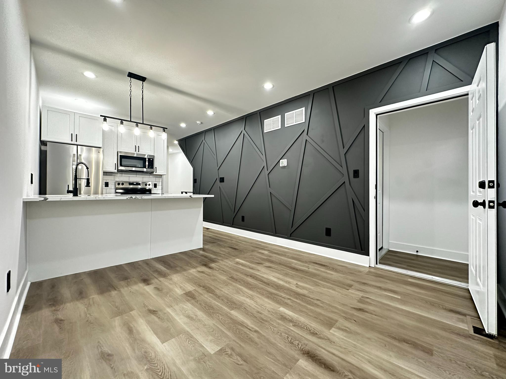 a view of kitchen with stainless steel appliances kitchen island granite countertop cabinets and wooden floor