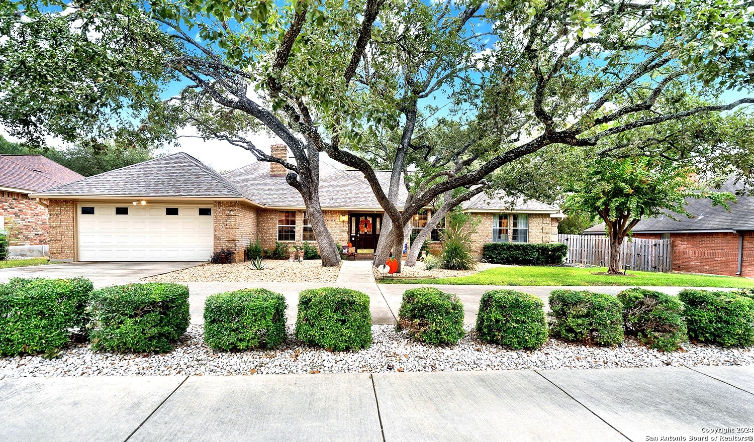 a front view of a house with a garden and trees