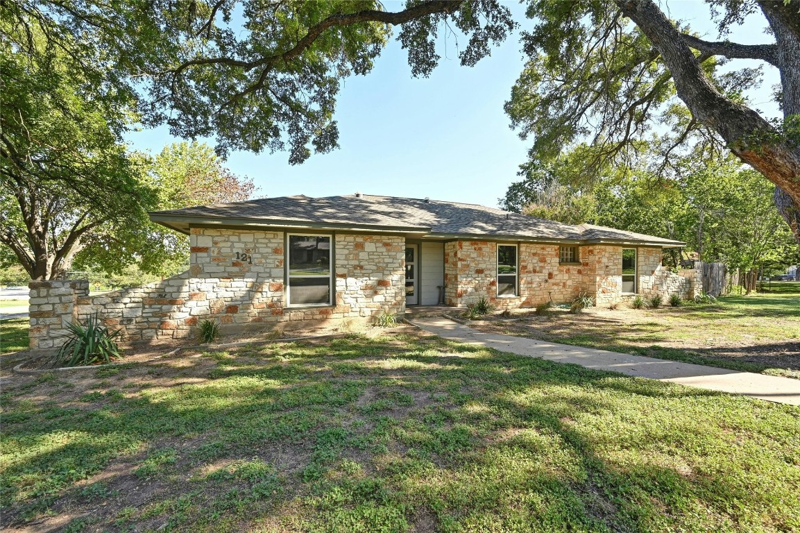 a front view of a house with a garden and trees