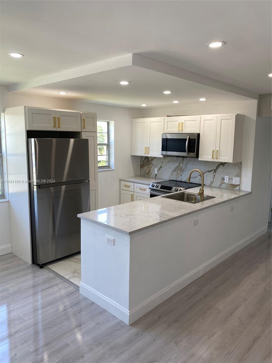 a kitchen with kitchen island granite countertop a refrigerator and a sink