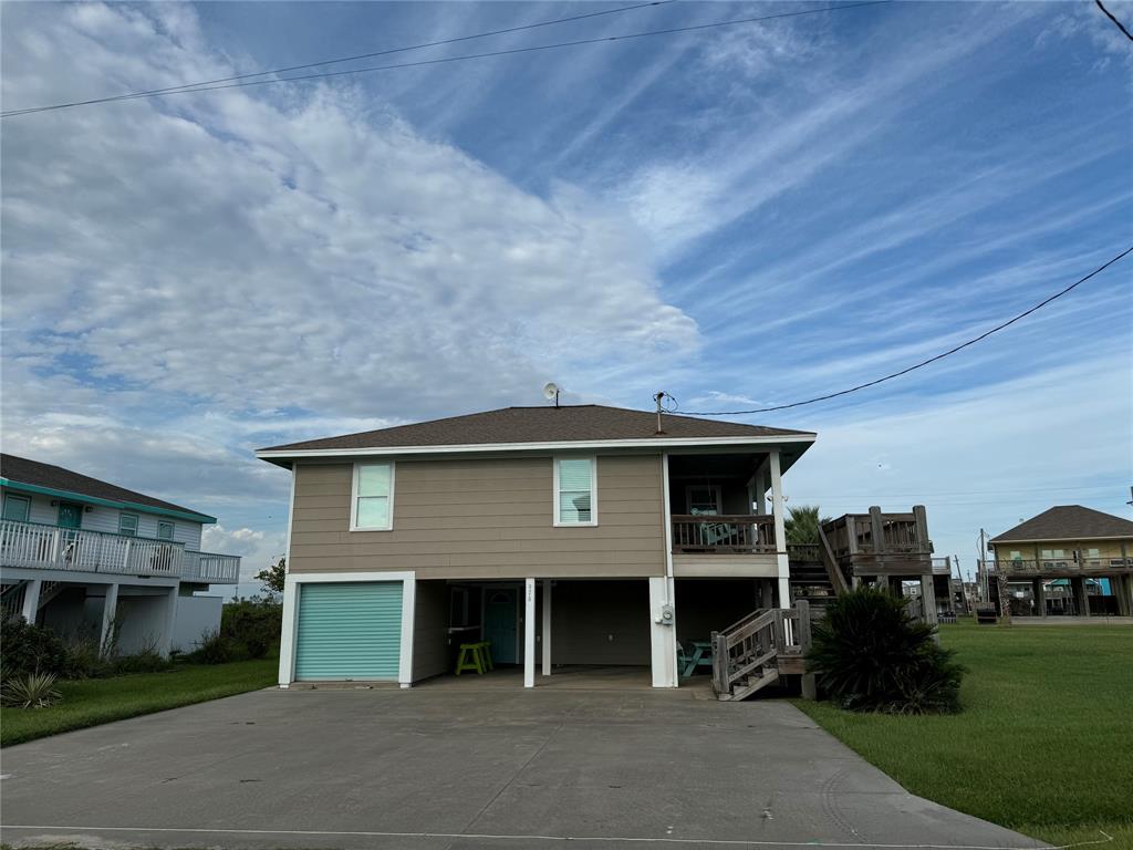 Welcome to this inviting coastal retreat featuring a spacious driveway, an integrated garage, and a charming upper-level balcony promising serene outdoor living.