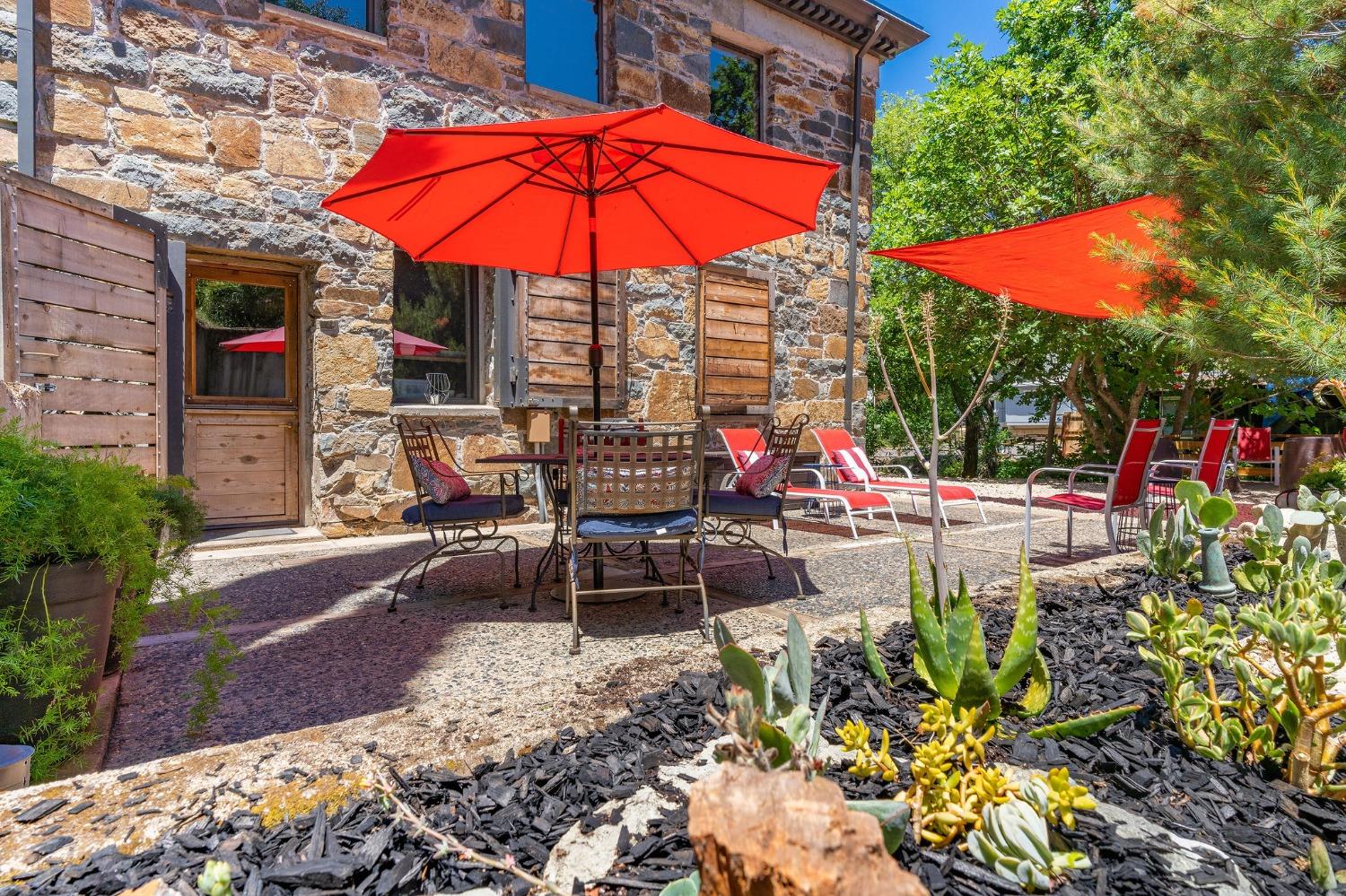 a view of a tables and chairs under an umbrella in backyard