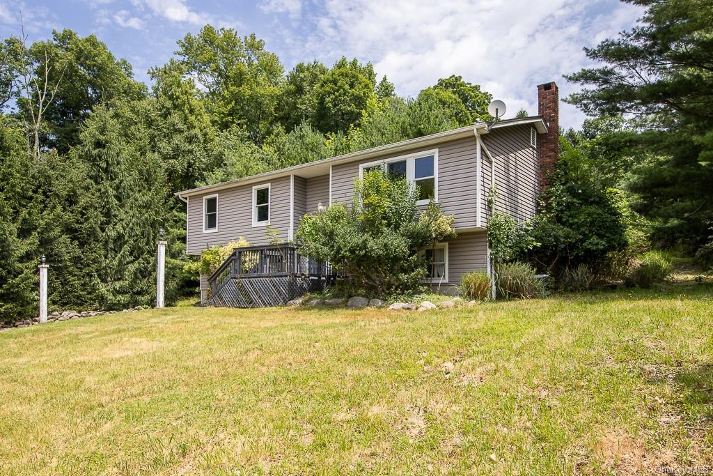 View of front of home featuring a front lawn and a wooden deck