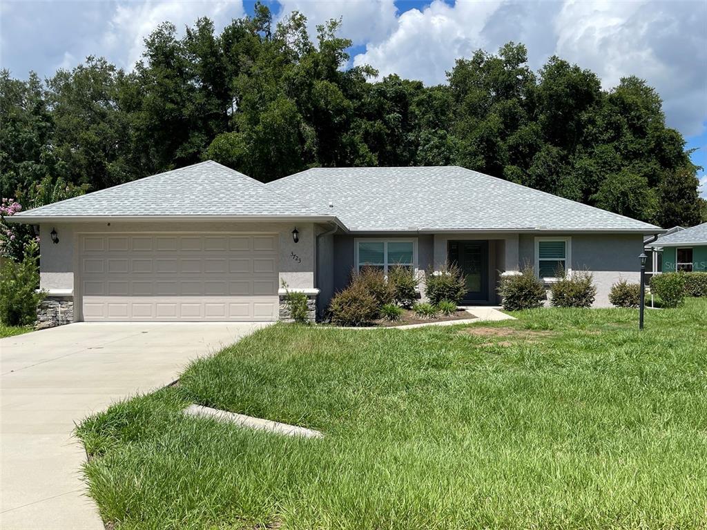 a front view of a house with swimming pool and green space