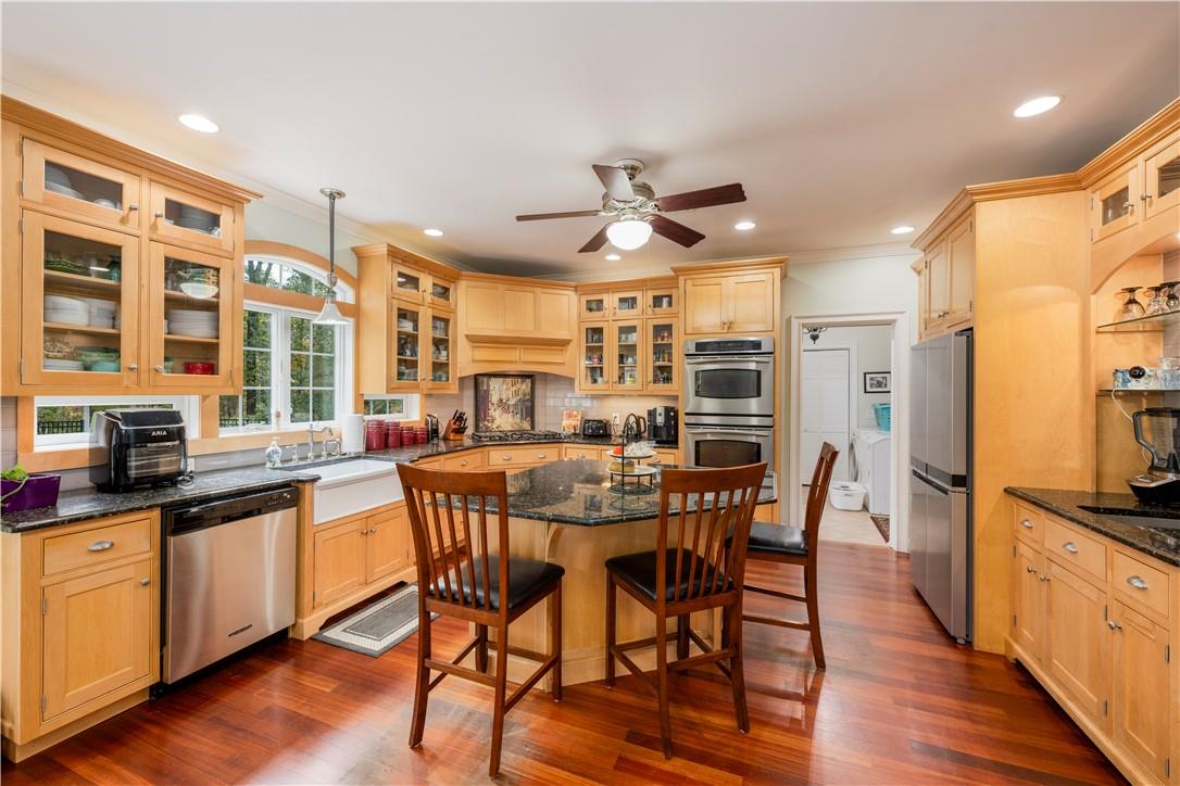 Kitchen with dark stone countertops, ceiling fan, dark hardwood / wood-style flooring, and stainless steel appliances