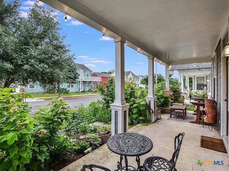 a view of a patio with table and chairs potted plants and large tree