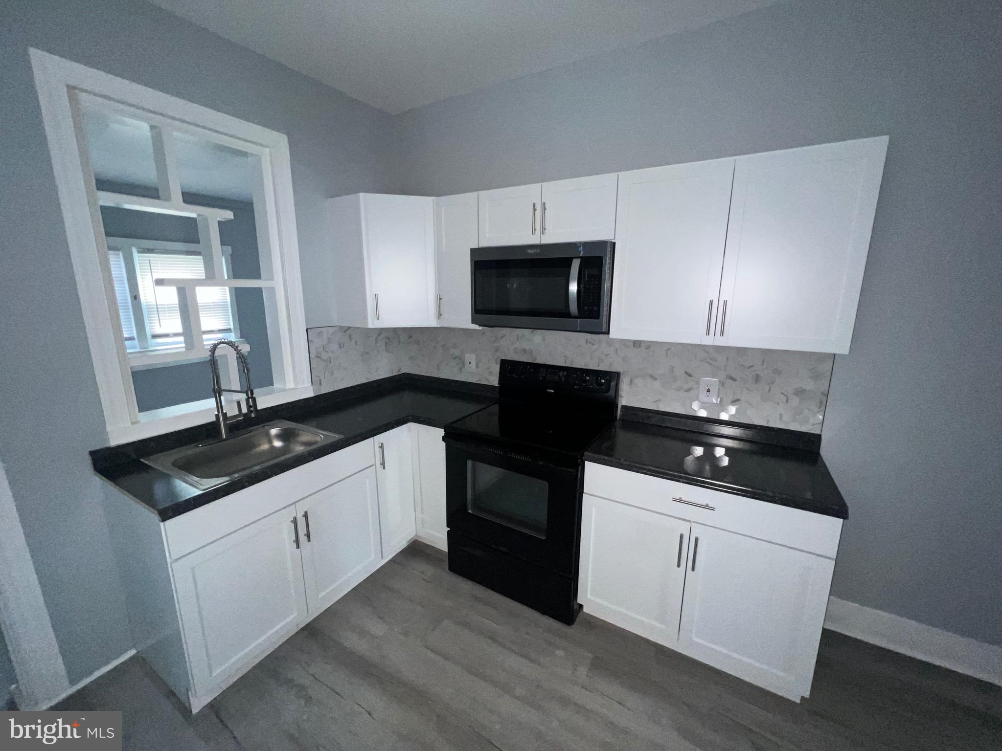 a kitchen with granite countertop white cabinets and black appliances