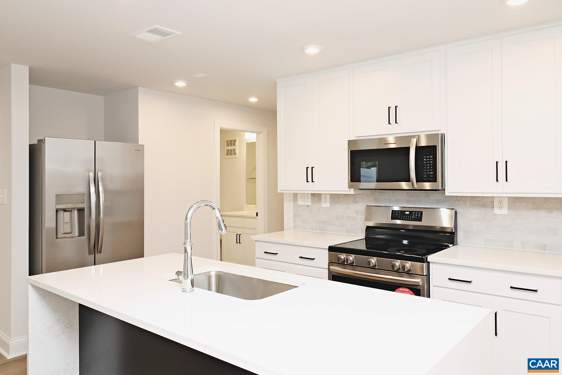 a kitchen with stainless steel appliances a stove a sink a microwave and cabinets