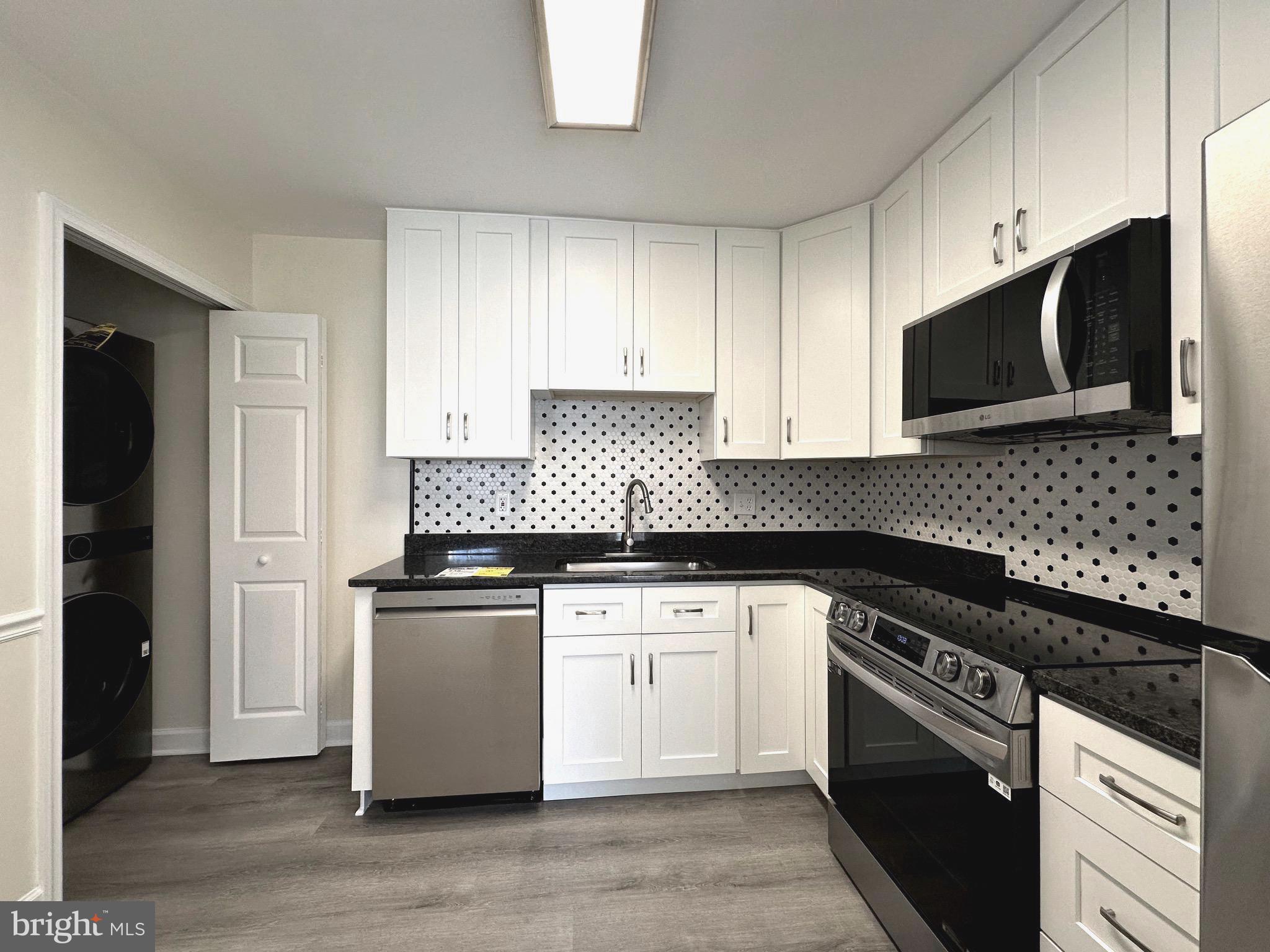 a kitchen with granite countertop cabinets stainless steel appliances and wooden floor