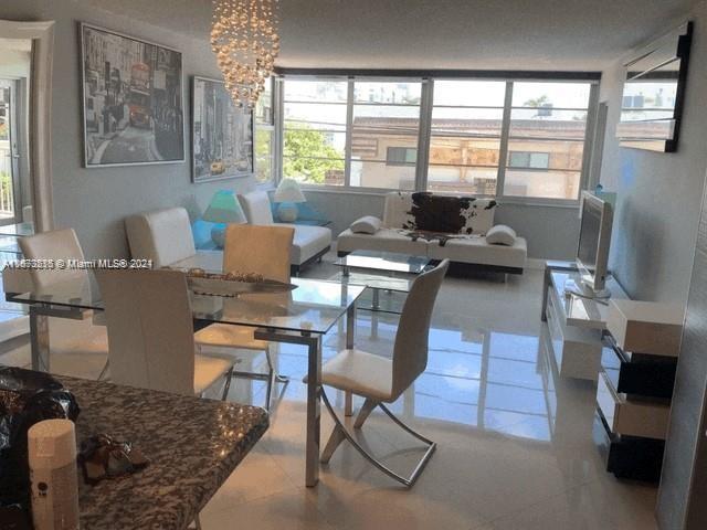 a living room with furniture floor to ceiling window and a flat screen tv