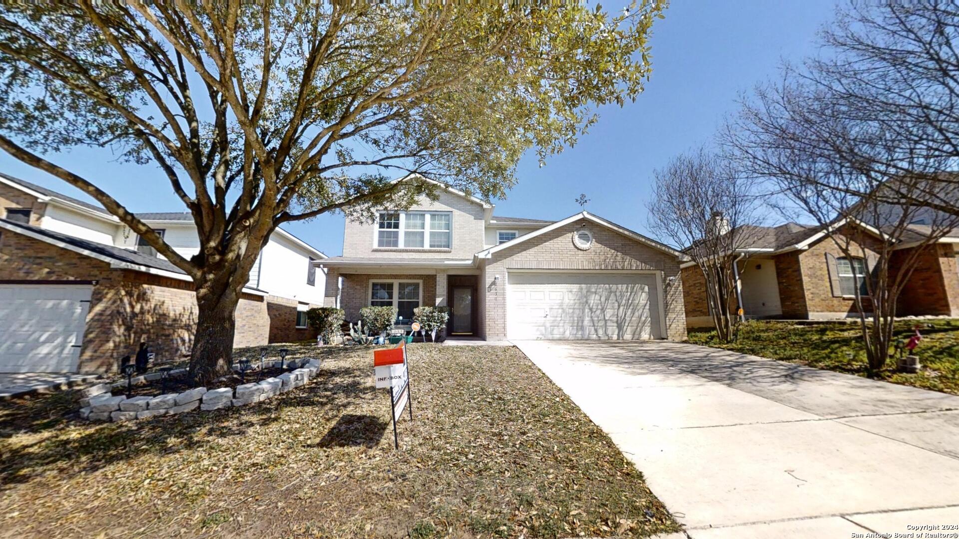 a front view of a house with a yard and large trees