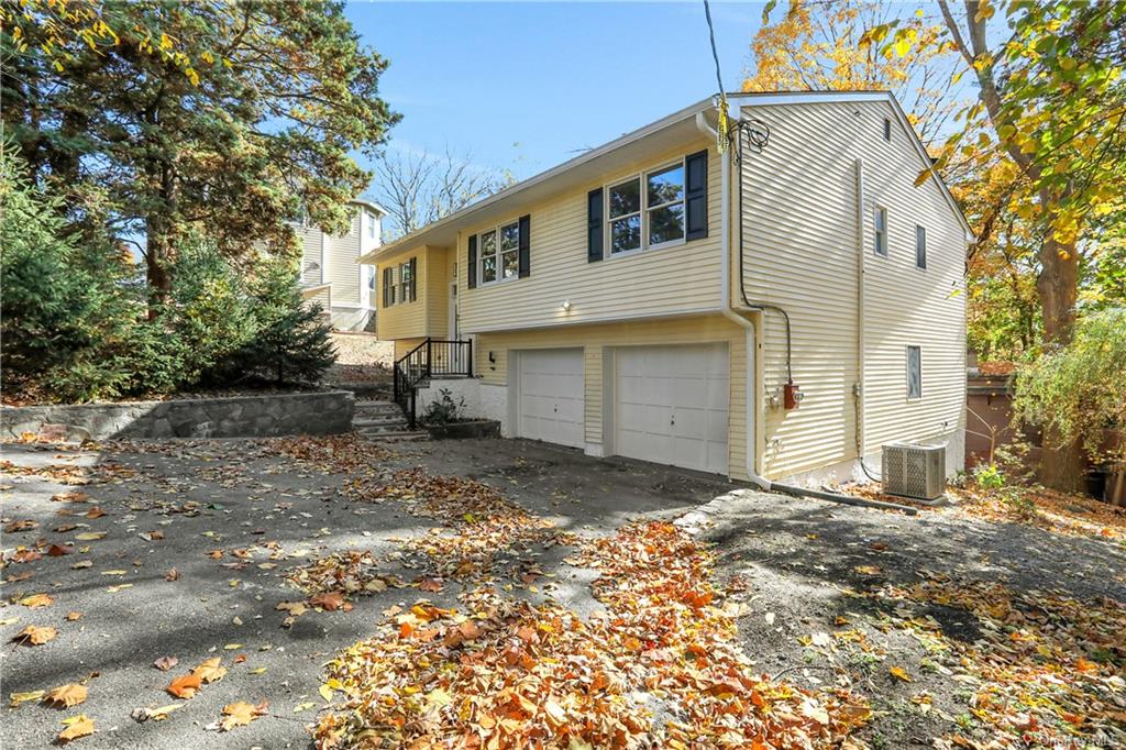 View of property exterior with cooling unit and a garage