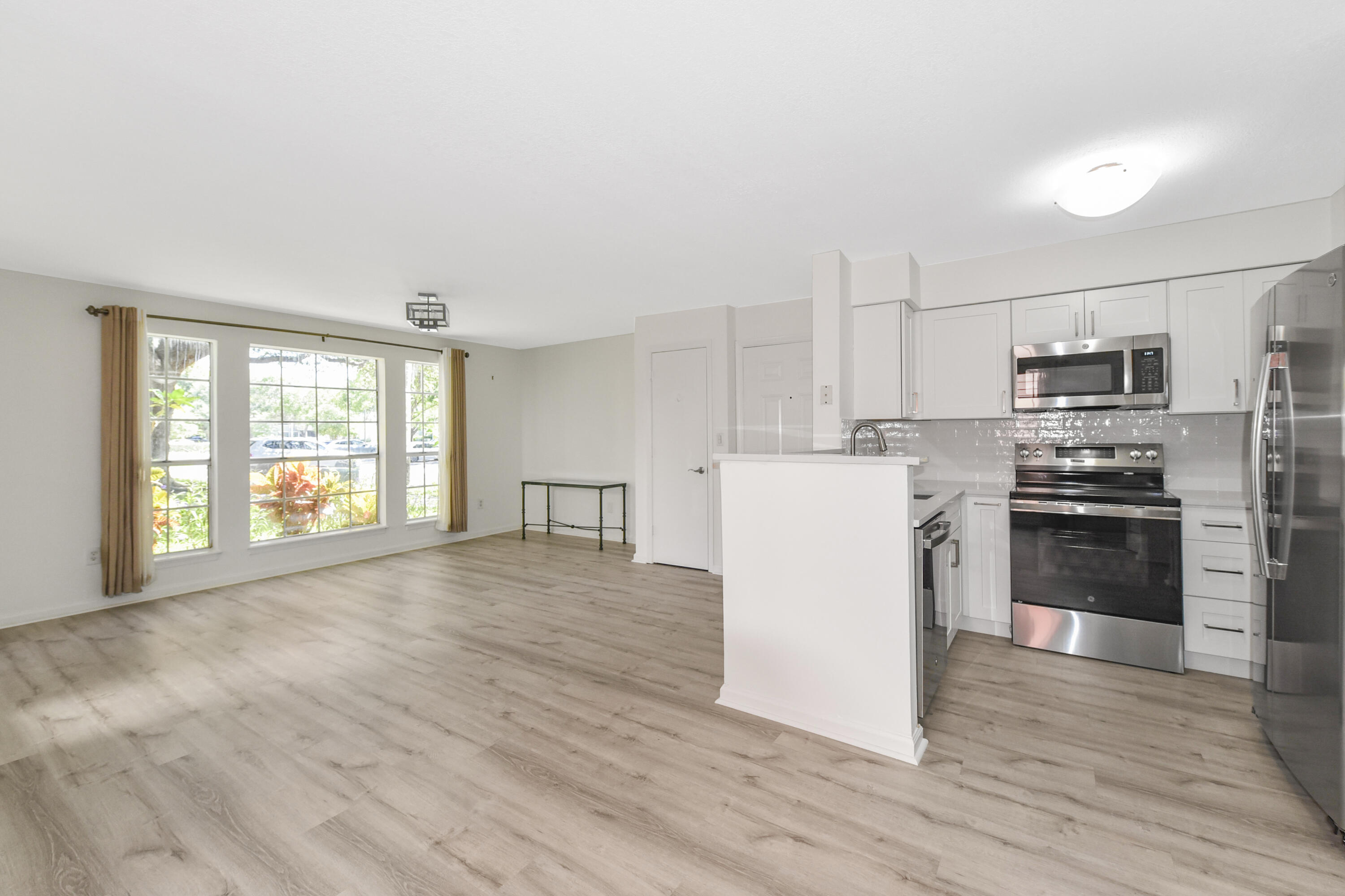 a kitchen with a refrigerator a stove top oven and a dishwasher next to a large window