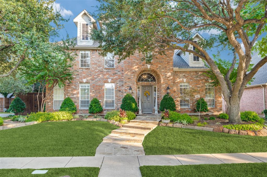 a front view of a house with a garden and tree