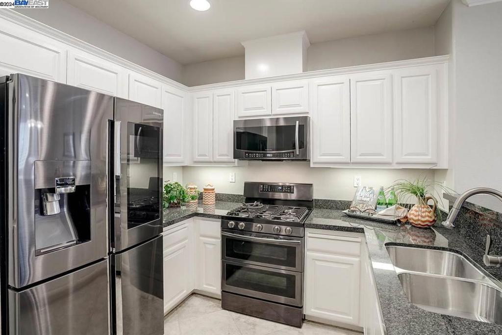 a kitchen with refrigerator a microwave a sink and cabinets