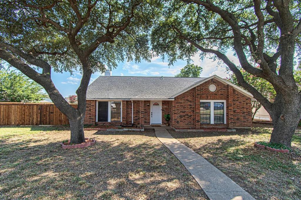 a front view of a house with a yard and large tree