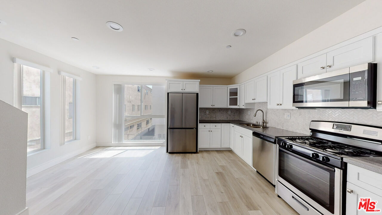 a kitchen with stainless steel appliances a refrigerator a stove top oven and sink