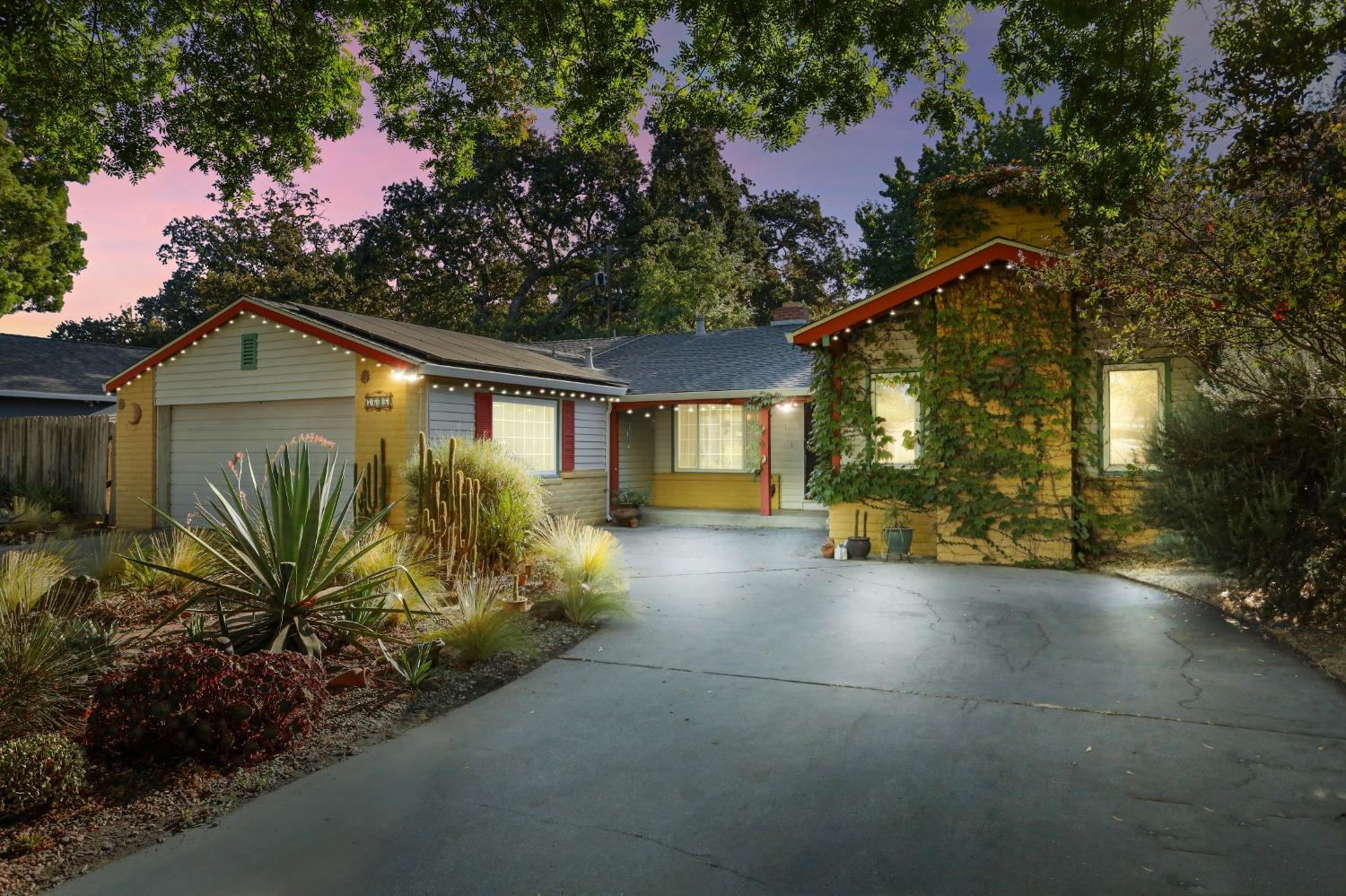 a view of a house with a small yard and a large tree