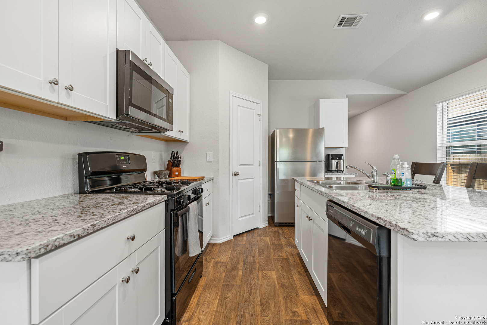 a kitchen with stainless steel appliances granite countertop a sink stove microwave and refrigerator