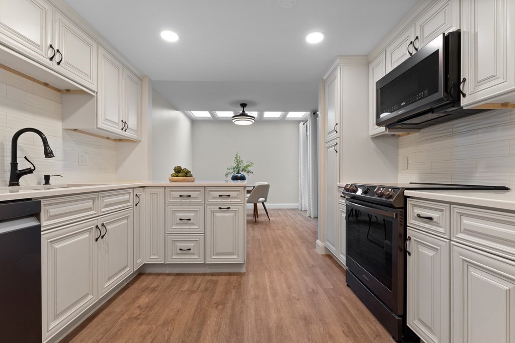 a kitchen with cabinets stainless steel appliances and wooden floor