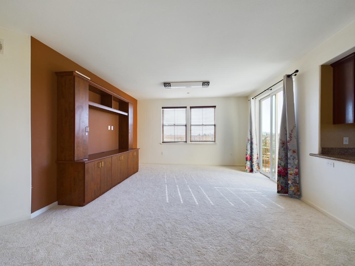 a view of an empty room with a window and a kitchen