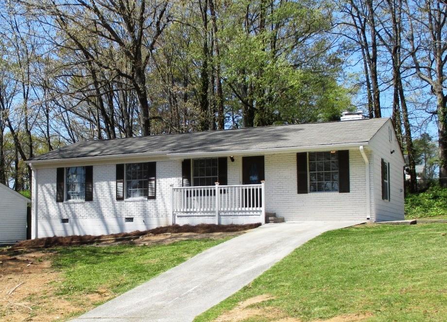 a view of a house with a yard and a large tree