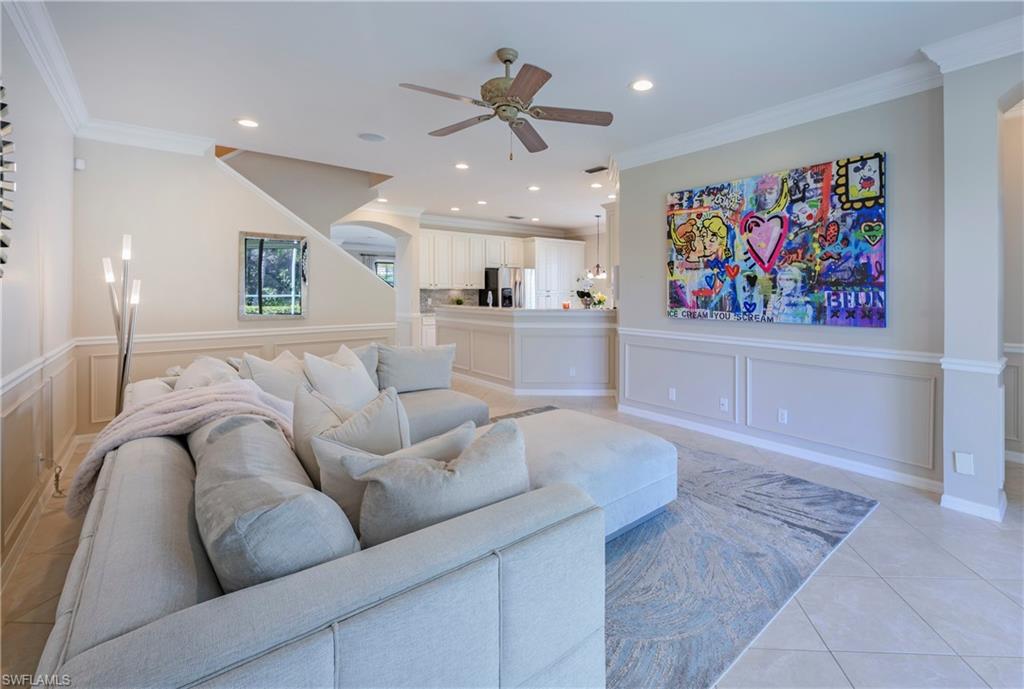 Living room featuring ceiling fan, light tile patterned flooring, and ornamental molding