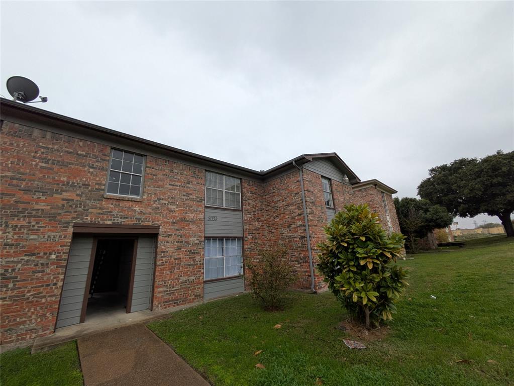 a brick house with a yard and a garden