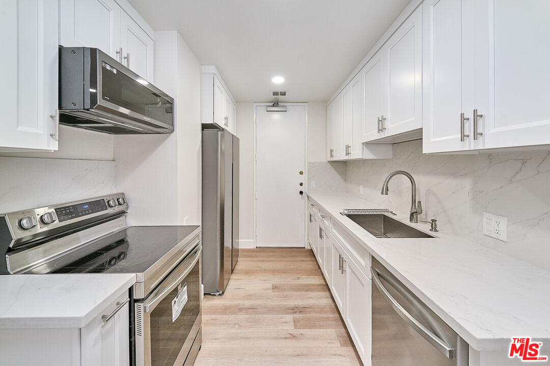 a kitchen with stainless steel appliances a sink stove and refrigerator