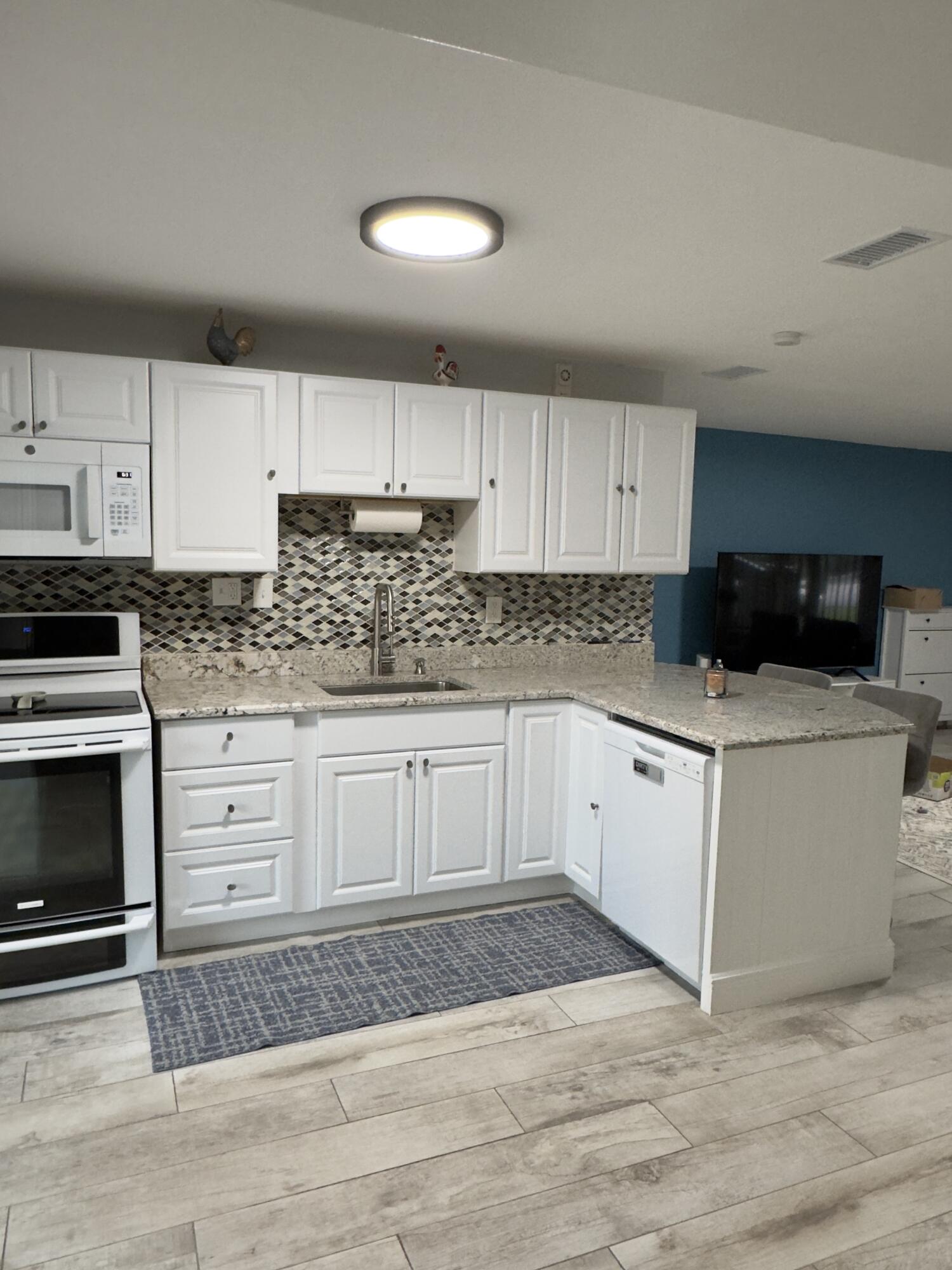 a kitchen with granite countertop a sink cabinets and stainless steel appliances