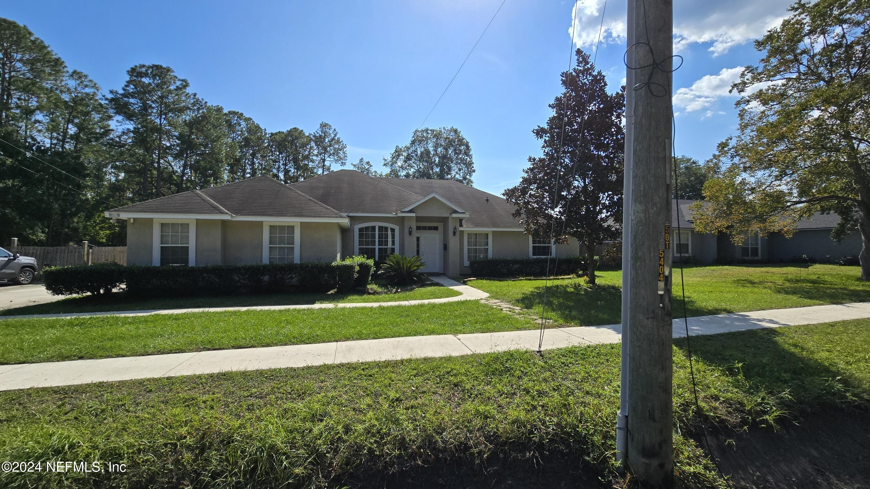 a view of a house with a big yard plants and large trees