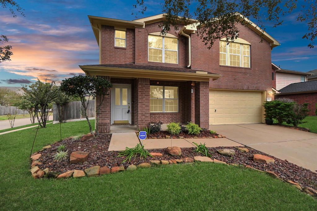 You're looking at a two-story brick home with an attached garage, featuring manicured landscaping.