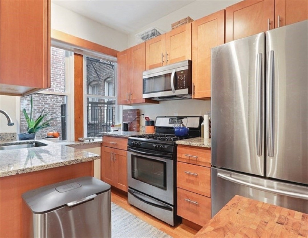 a kitchen with stainless steel appliances granite countertop a refrigerator sink and stove