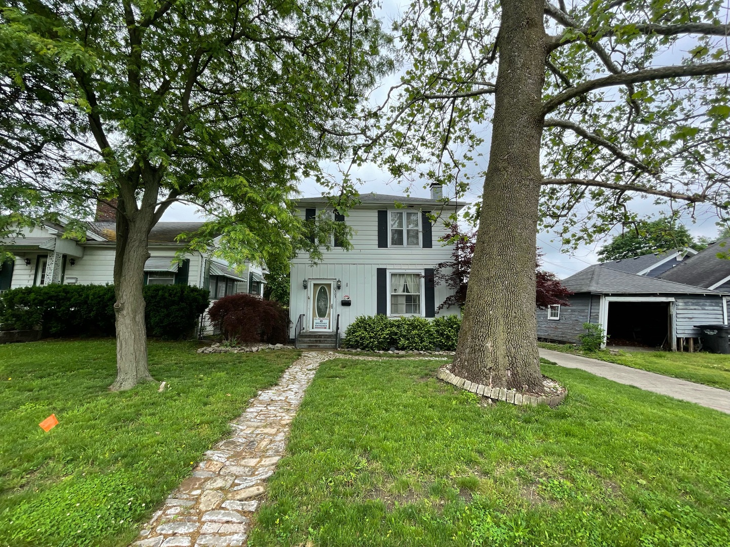a view of a house with a yard and a large tree
