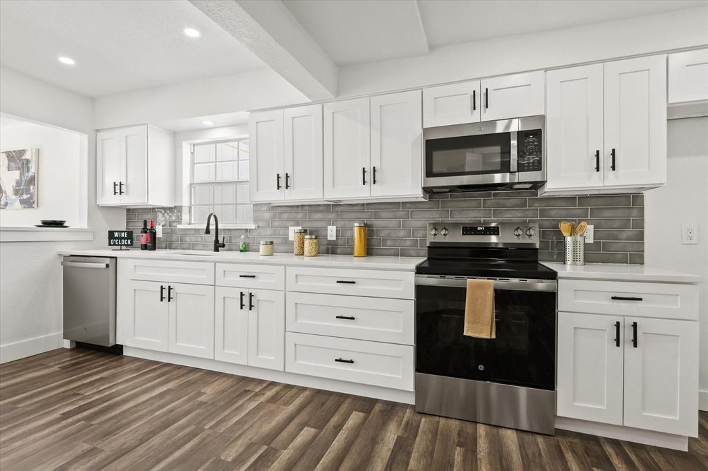 a kitchen with stainless steel appliances granite countertop a stove a sink and white cabinets