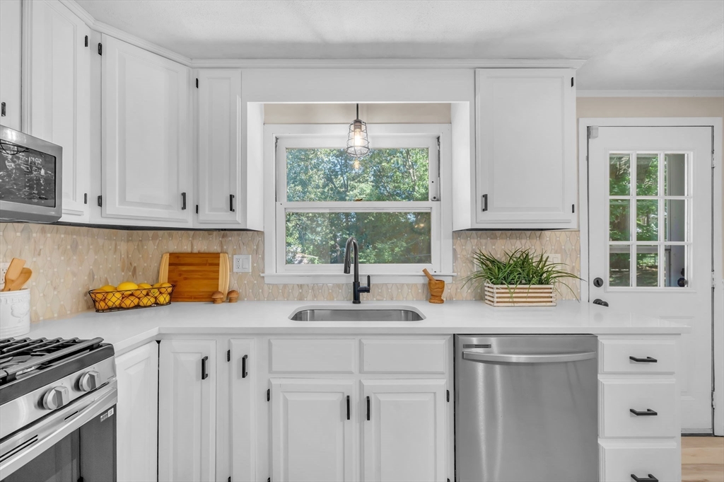 a kitchen with stainless steel appliances white cabinets a stove a sink and a window