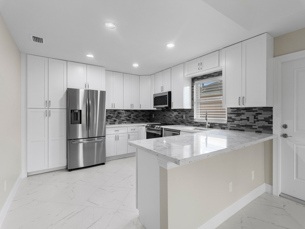 a kitchen with a refrigerator a sink a stove top oven and cabinets