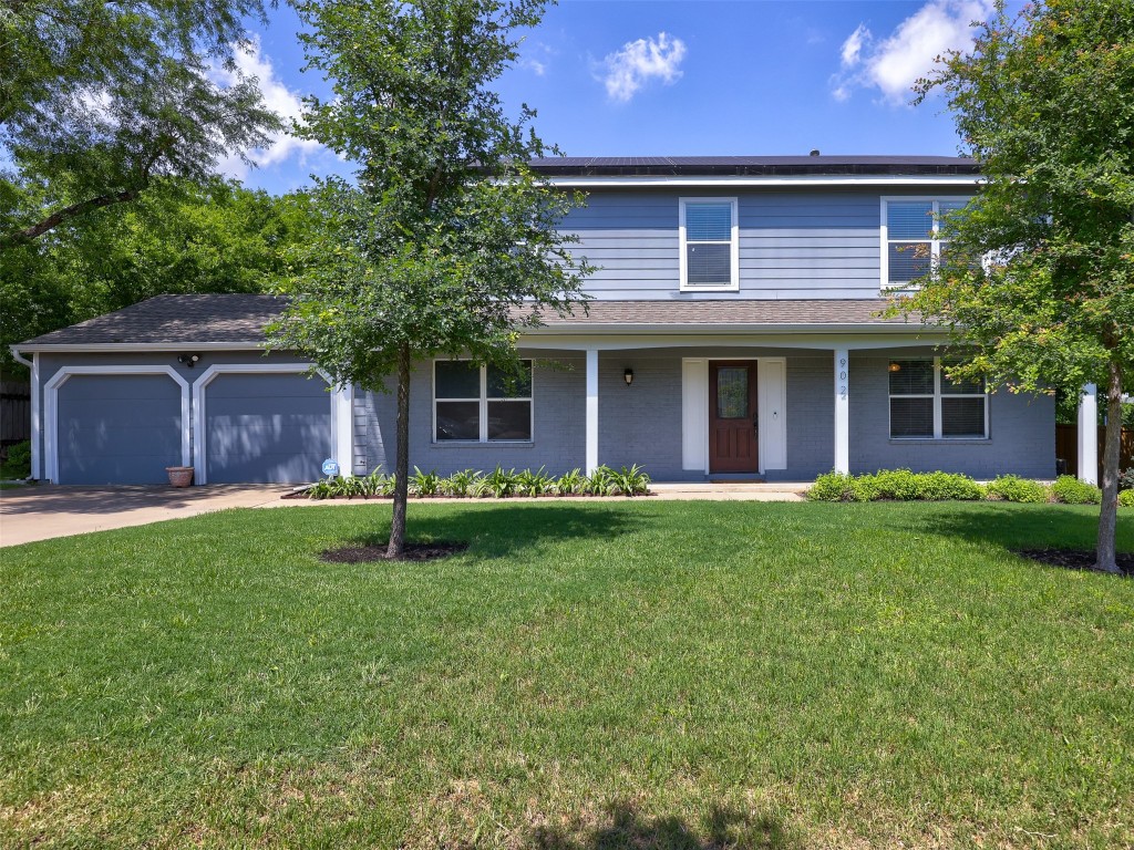 a brick house with a large tree in front of it