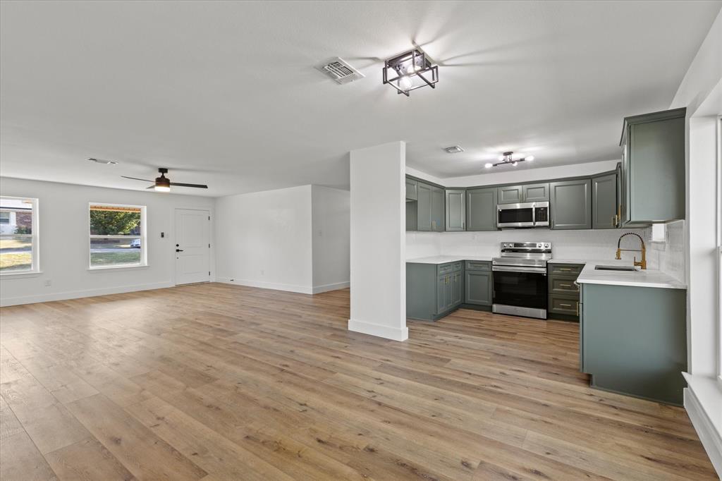 a view of a kitchen with a sink stove cabinets and empty room