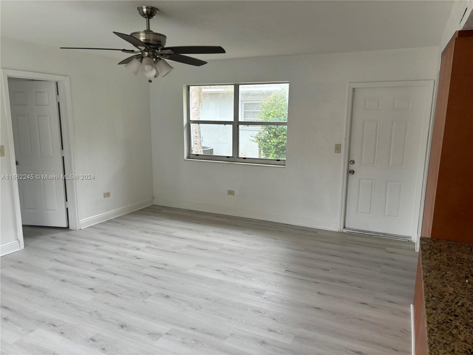 an empty room with wooden floor fan and windows