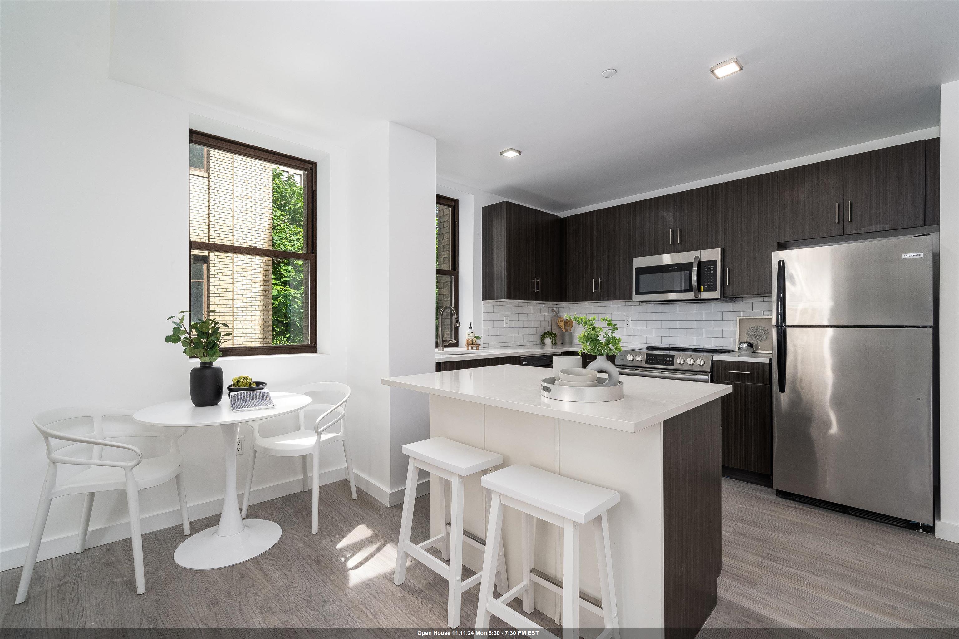 a kitchen with stainless steel appliances a sink a microwave a refrigerator and chairs