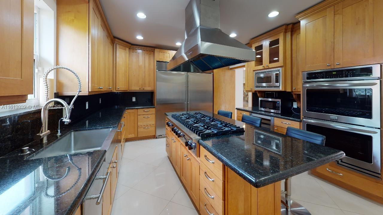 a kitchen with kitchen island granite countertop a stove and a sink