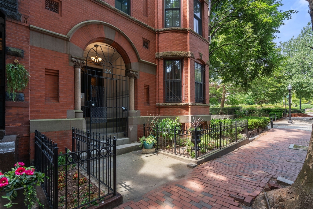 a view of a brick house with plants and a bench in front of it