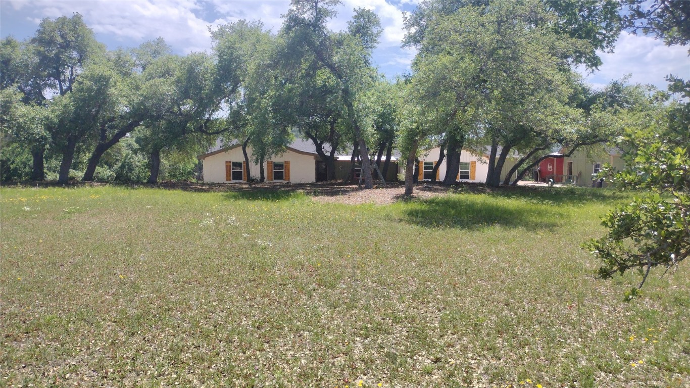 a view of a house with a yard and large trees