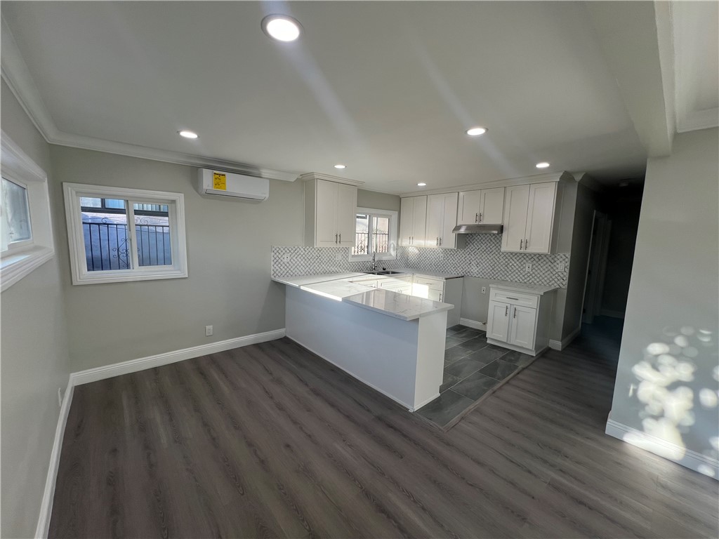 a large white kitchen with wooden floors and stainless steel appliances