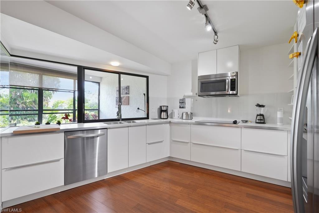 a large white kitchen with a large window a sink and a counter space