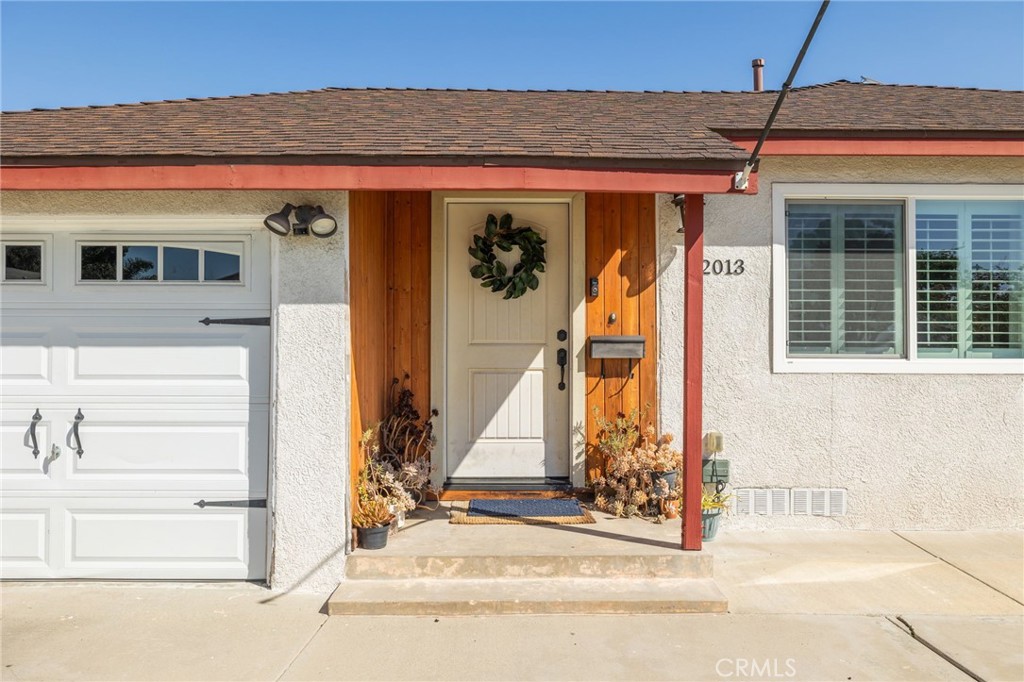 a view of a house with a small yard and potted plants