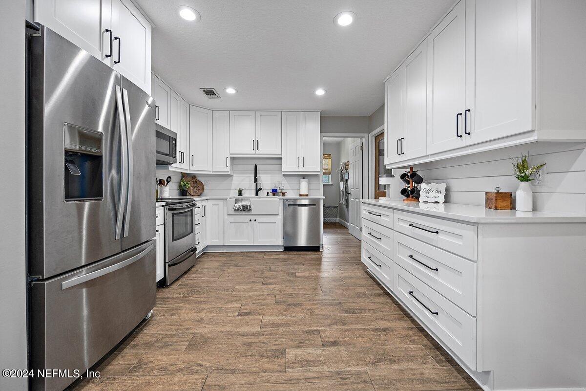 a kitchen with white cabinets and stainless steel appliances